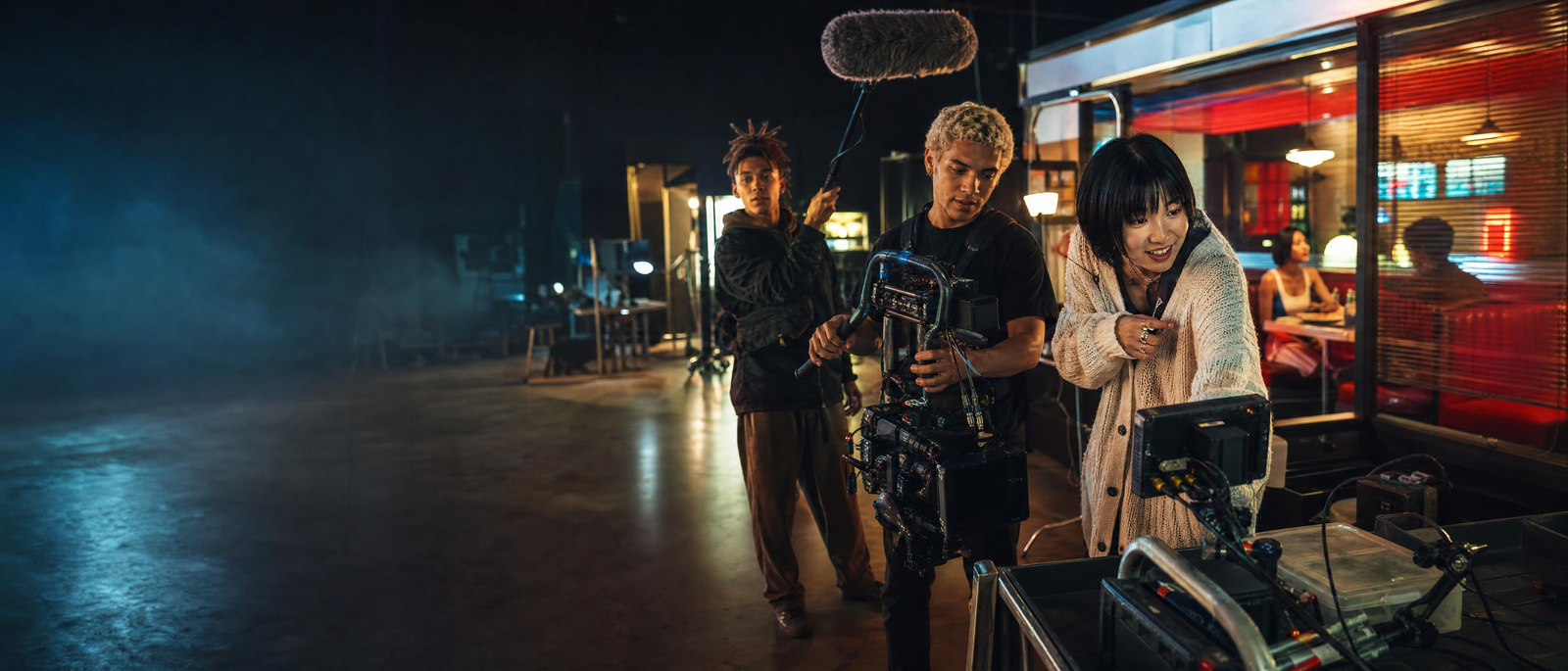 A young crew directing a short film shoot in a neon-lit studio