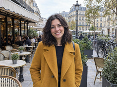 Smiling woman in a mustard coat on a busy café terrace