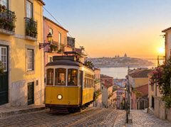 Yellow tram climbing a steep old-town street at golden hour