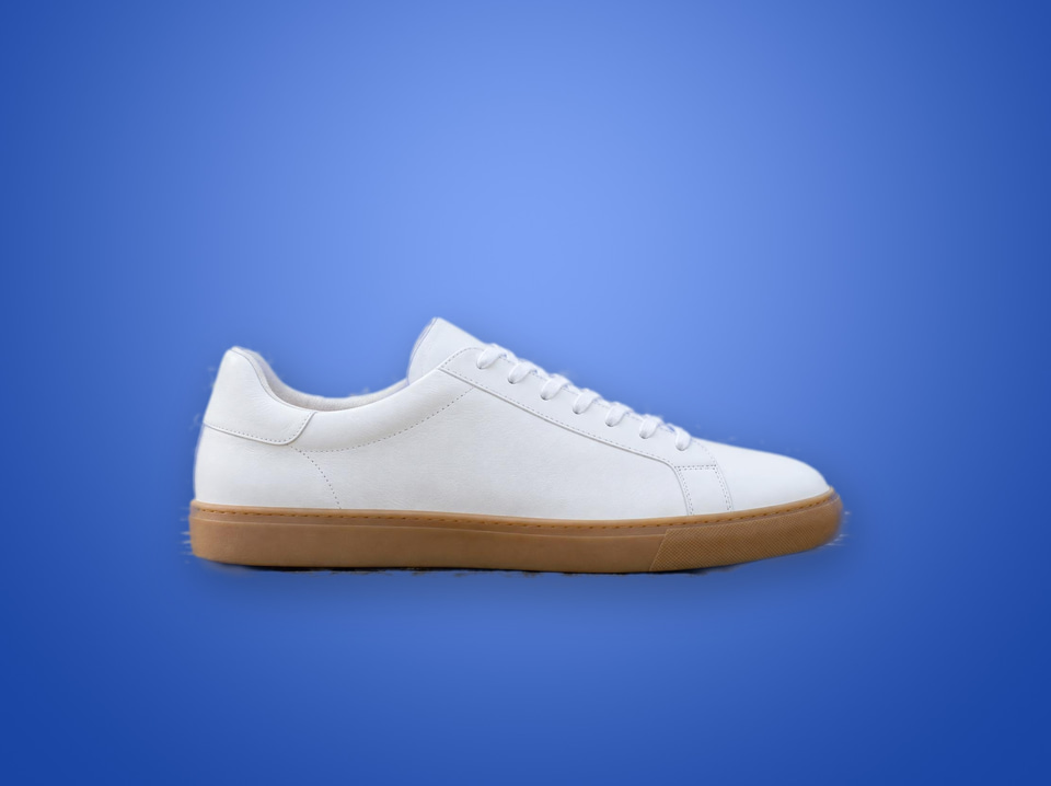 After: A white leather sneaker on a weathered wooden bench in a park — new background colour