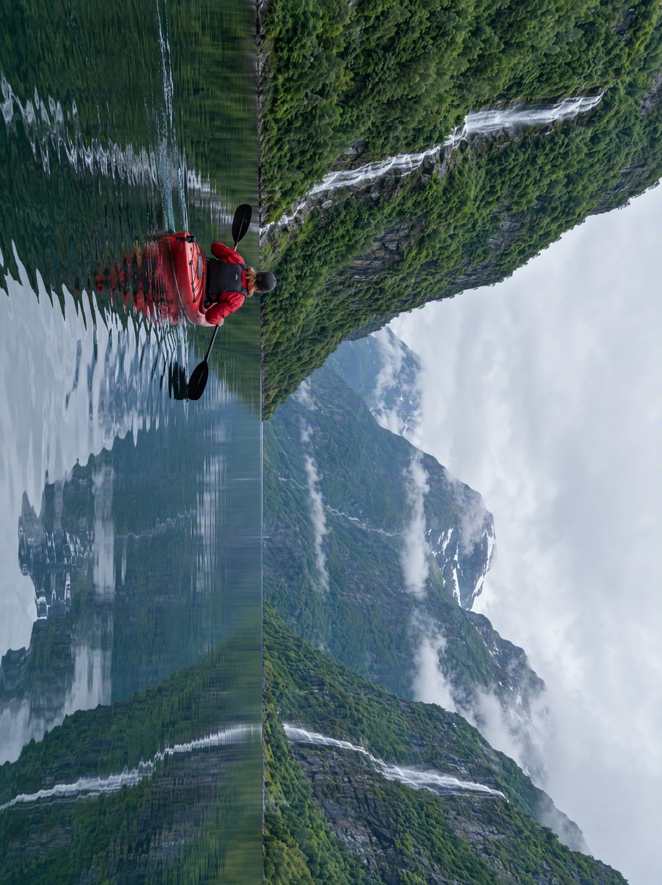 After: Red kayak on a still fjord between steep green mountains — rotated