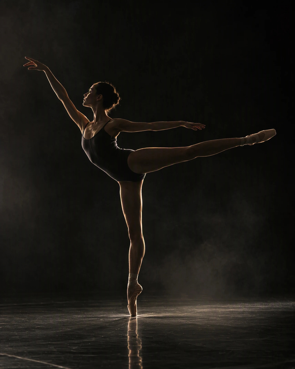 A dancer frozen mid-arabesque in a black studio
