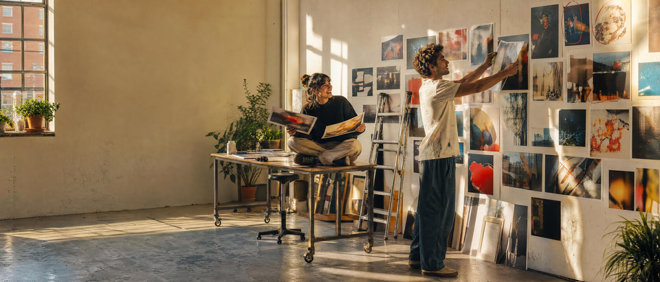 Illustration: a creator pinning favourite prints to a wall