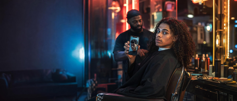 A young man in a barber's chair showing a new haircut he tried on his own photo