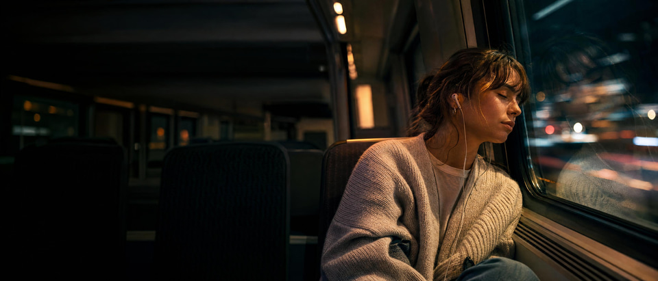 A young woman listening to music on a night train